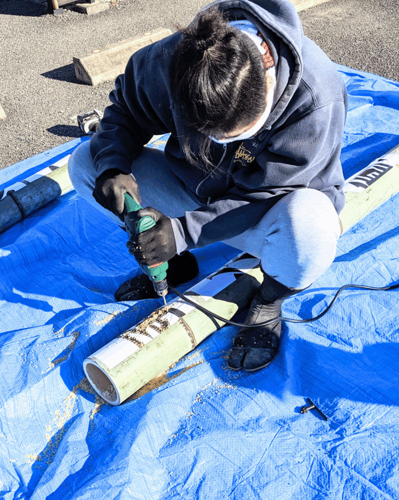 男性が竹にドリルで穴を開け、竹灯りの飾りを作っています。